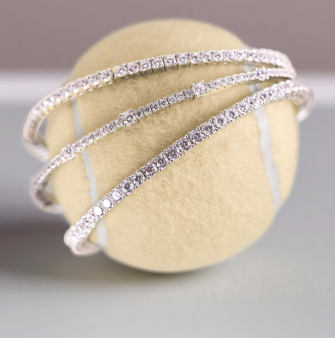 Lafonn simulated diamond tennis bangles in sterling silver, elegantly wrapped around a tennis ball, showcasing brilliant sparkle and timeless design.