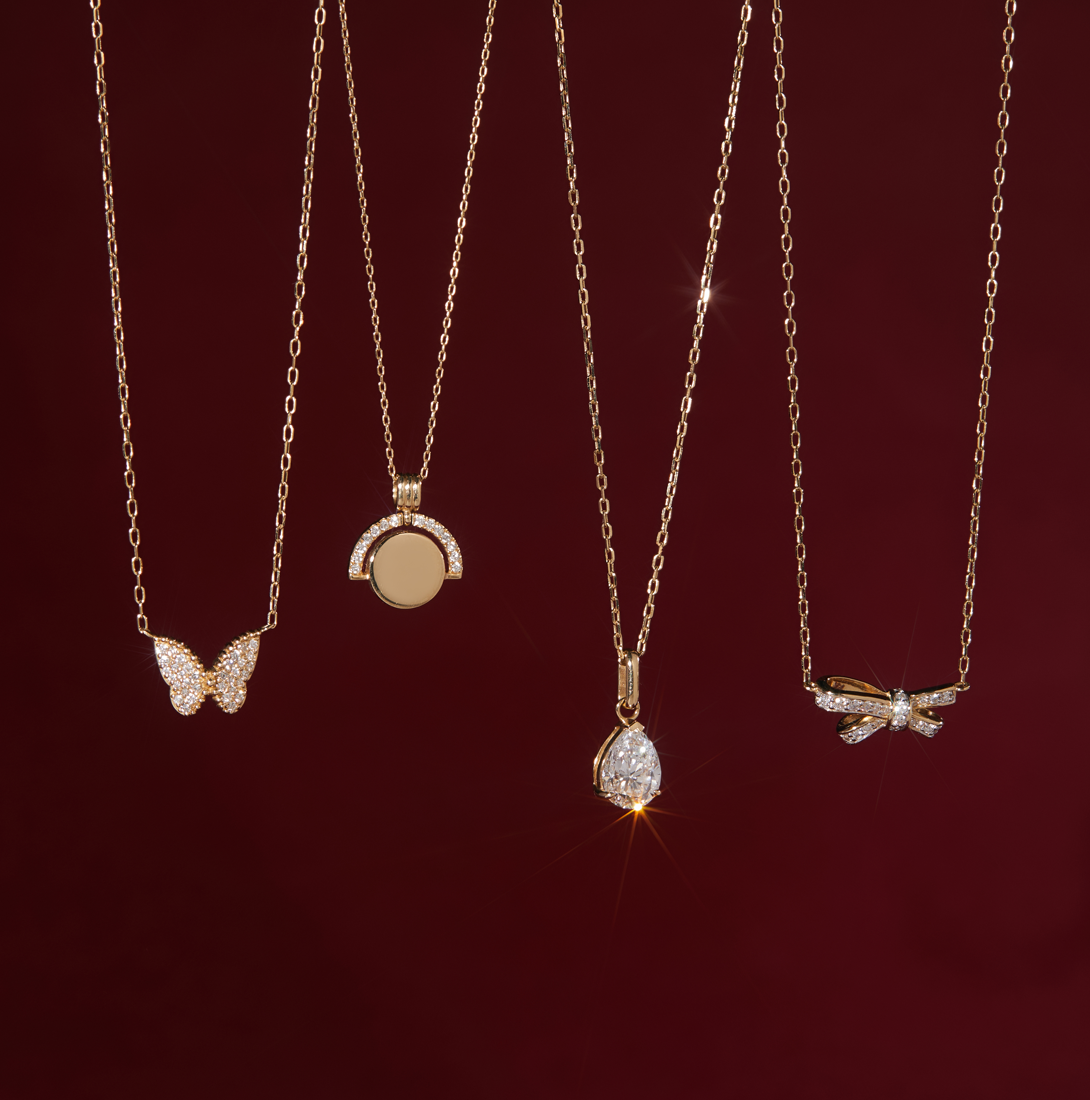Aurelie Gi 14k solid gold and diamond pendant necklaces displayed against a rich burgundy background — featuring pavé butterfly, modern circle, pear-shaped diamond, and delicate dragonfly designs for a refined and timeless look.