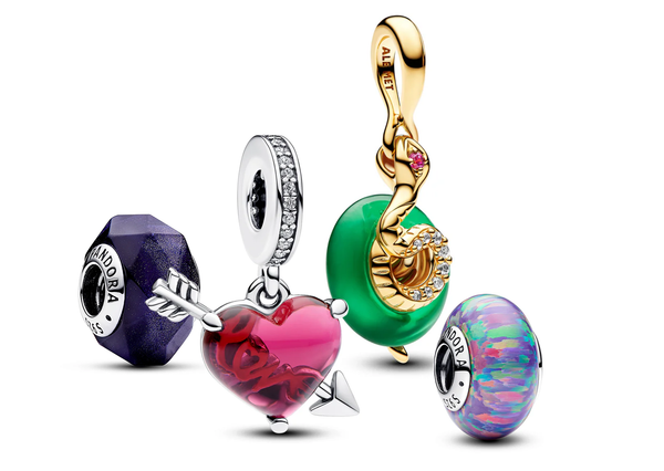 A collection of Murano glass Pandora Charms featuring a dangle snake charm themed for the Lunar Year, an opalescent purple charm, and a red heart & arrow dangle charm.