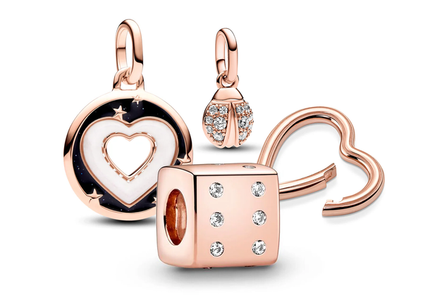 A collection of rose gold-plated Pandora Charms including a hearts medallion charm, sparkling ladybug dangle charm, and styling heart connector. 