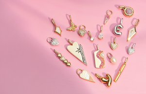 Colorful pop charms arranged in a heart shape on a pink background, illuminated by sunlight.