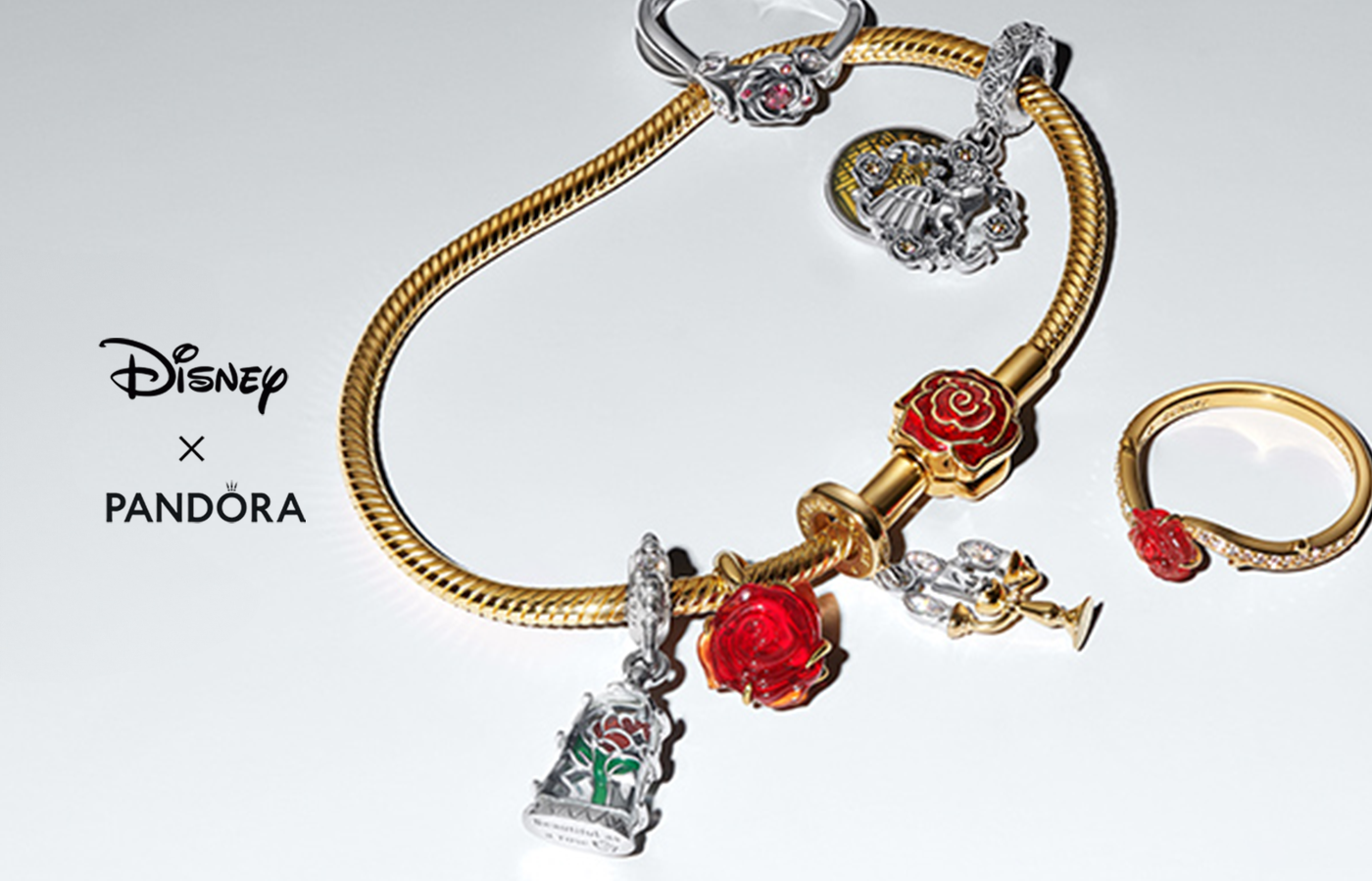 Disney x Pandora Beauty and the Beast jewelry collection featuring a gold snake chain bracelet with red rose charms, Lumière charm, enchanted rose dangle, and matching gold ring with red rose detail.