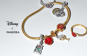 Disney x Pandora Beauty and the Beast jewelry collection featuring a gold snake chain bracelet with red rose charms, Lumière charm, enchanted rose dangle, and matching gold ring with red rose detail.