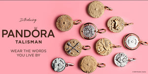 Pandora Talisman Collection featuring an assortment of gold and silver coin-shaped pendants with celestial, symbolic, and engraved designs, displayed on a pink background with the tagline “Wear the Words You Live By.”